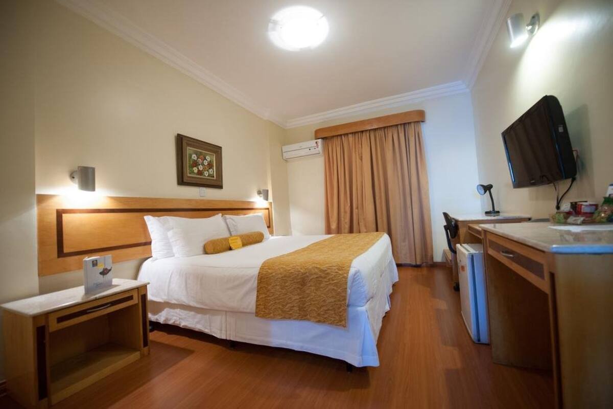 Ein Hotelzimmer mit Bett, Nachttisch, Schreibtisch, Stuhl und Fernseher.