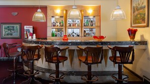 A bar area with a marble countertop, multiple bar stools, and a variety of bottles and glasses. - Carlton Plaza São José dos Campos (São José dos Campos)