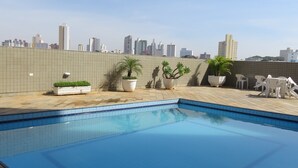 A rooftop swimming pool with tiled flooring, potted plants, and outdoor furniture. - Carlton Plaza São José dos Campos (São José dos Campos)