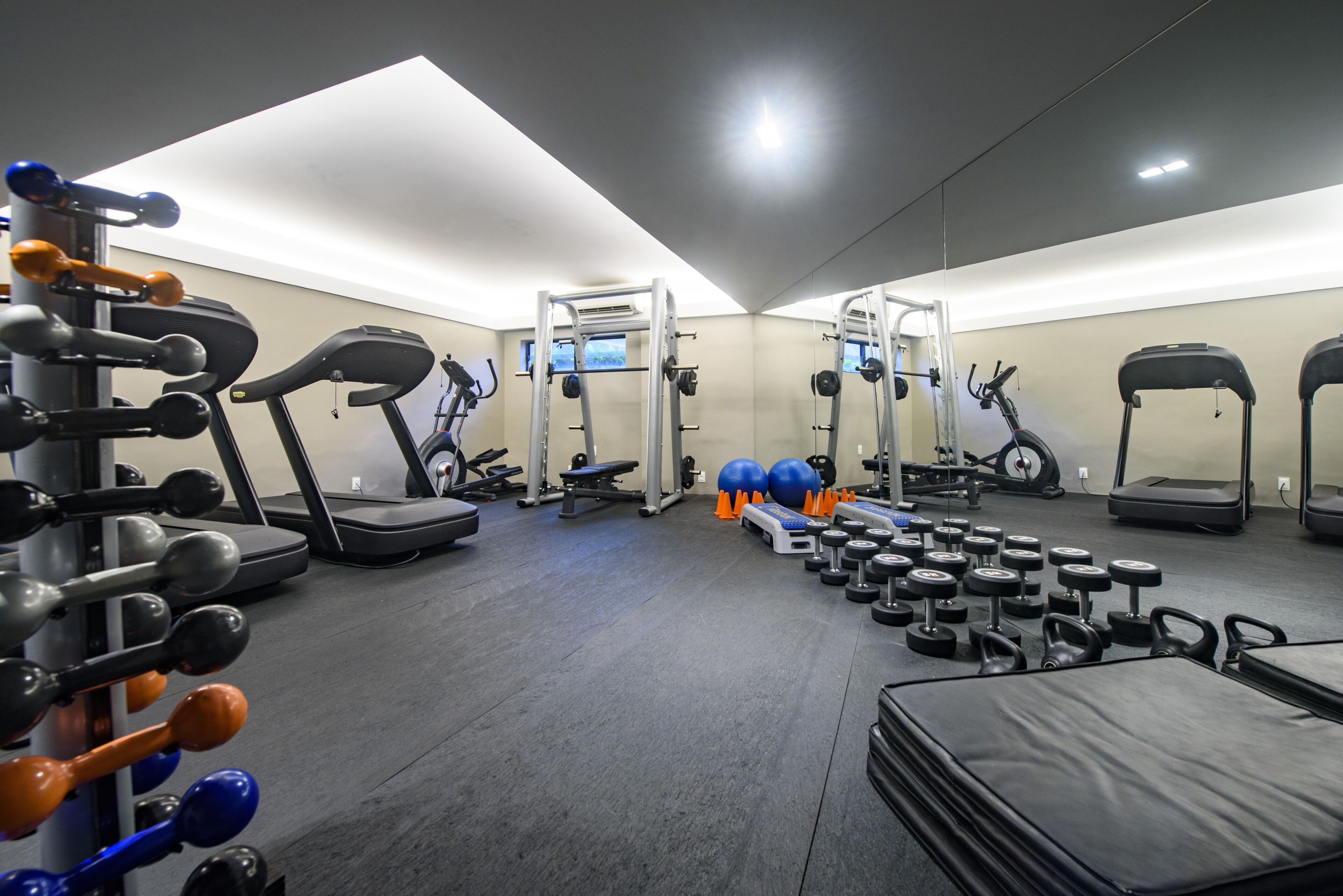 Un gimnasio con cintas de correr, máquinas de pesas y pesas sueltas.