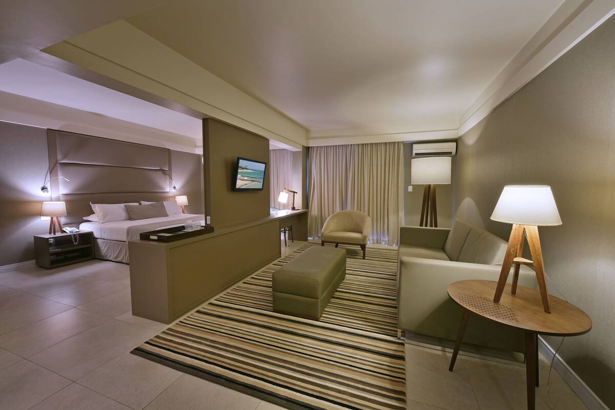 Habitación de hotel con cama, sofá, una pequeña mesa, una silla y un escritorio.