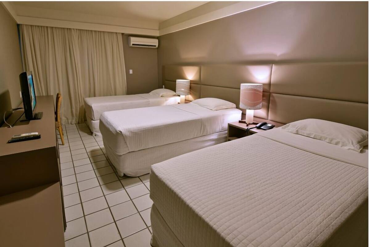 Habitación de hotel con dos camas, un escritorio, una silla y un televisor.