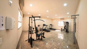 A spacious gym with various exercise equipment, including a treadmill, weight machines, and a pull-up bar.