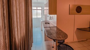 A modern kitchen with a central island, white cabinets, and a view to the dining area.