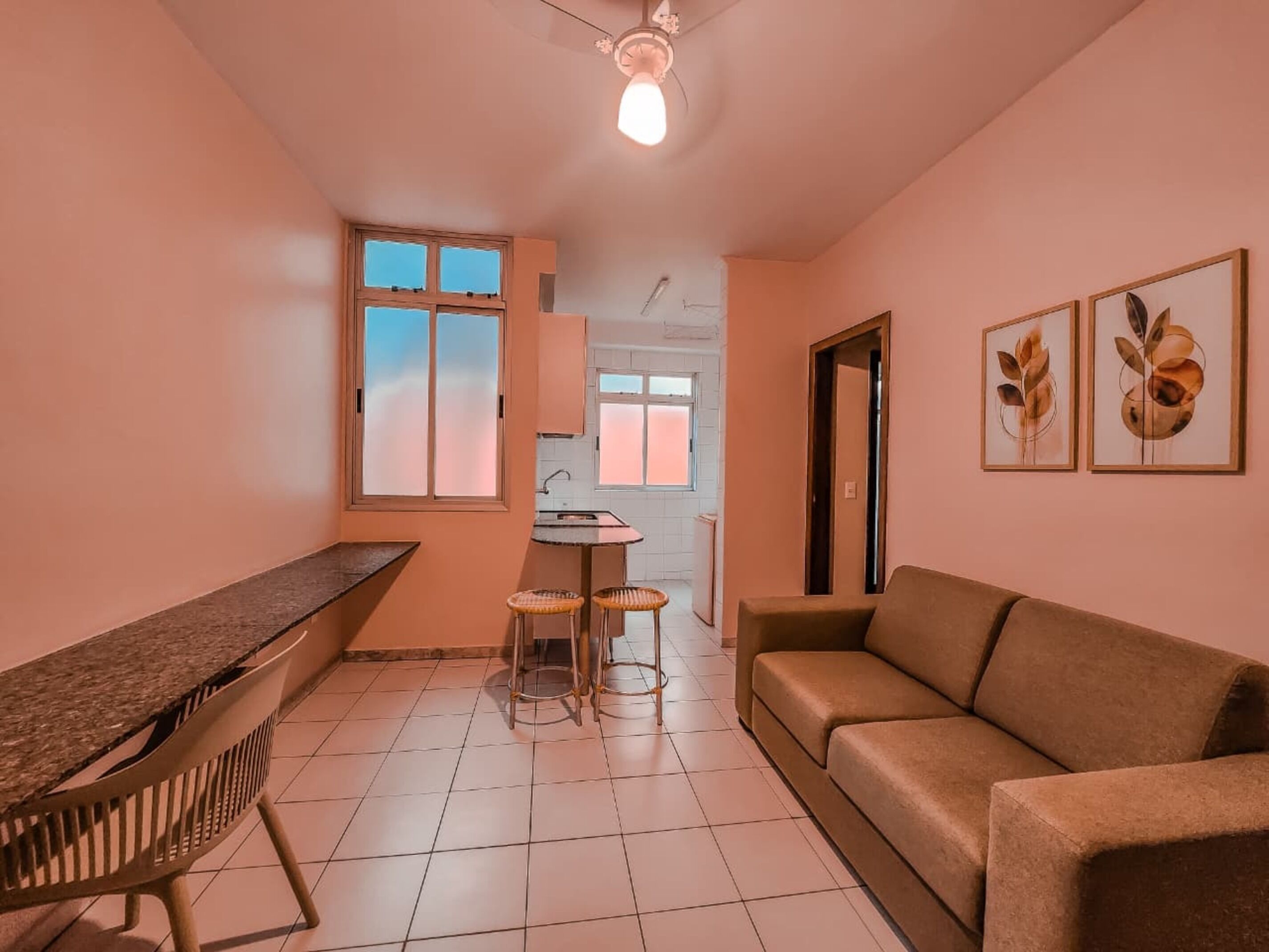 A compact living space with a kitchenette, a sofa, a dining table, and two chairs.