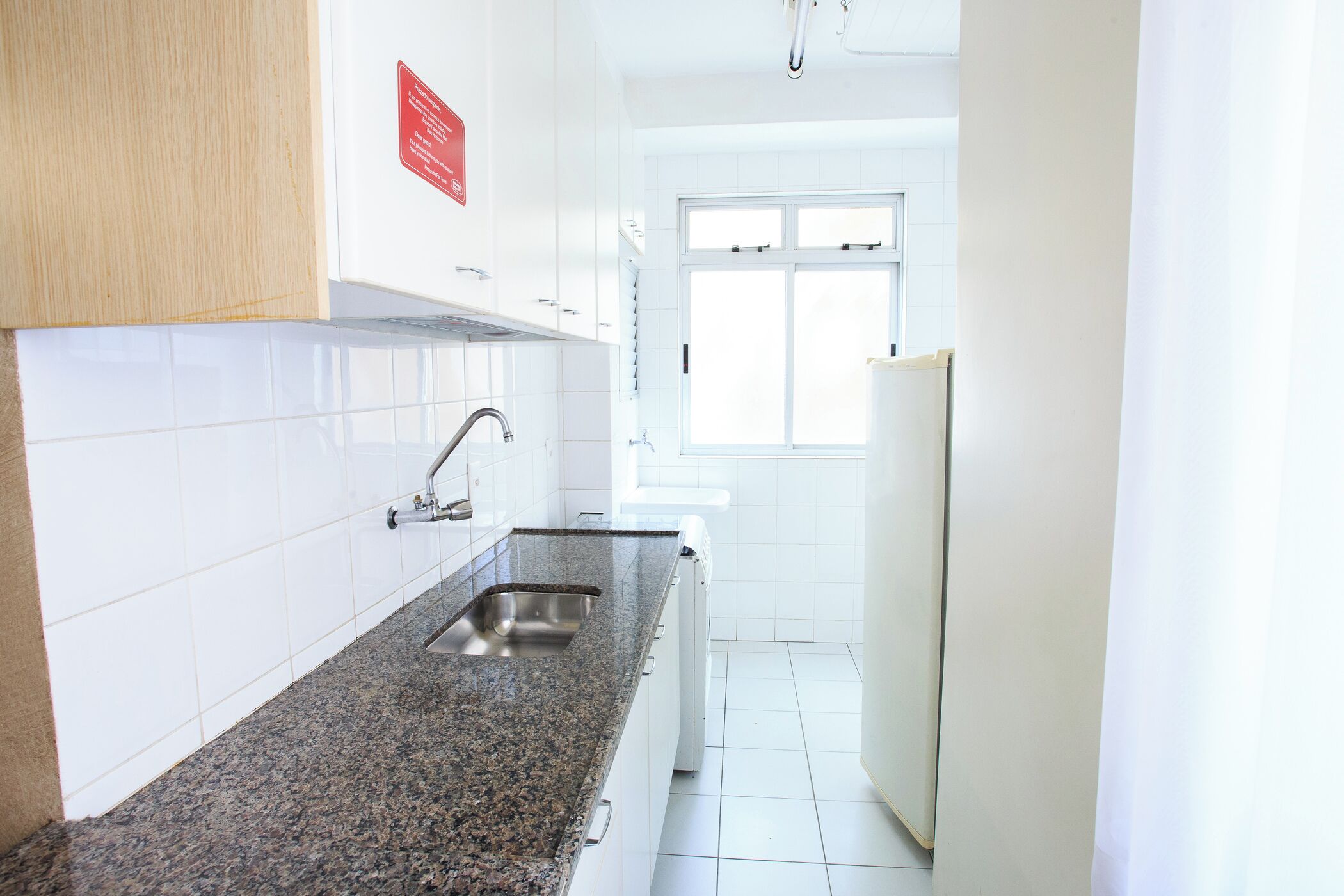 A modern kitchen with white cabinets, a granite countertop, a stainless steel sink, and a window providing natural light.