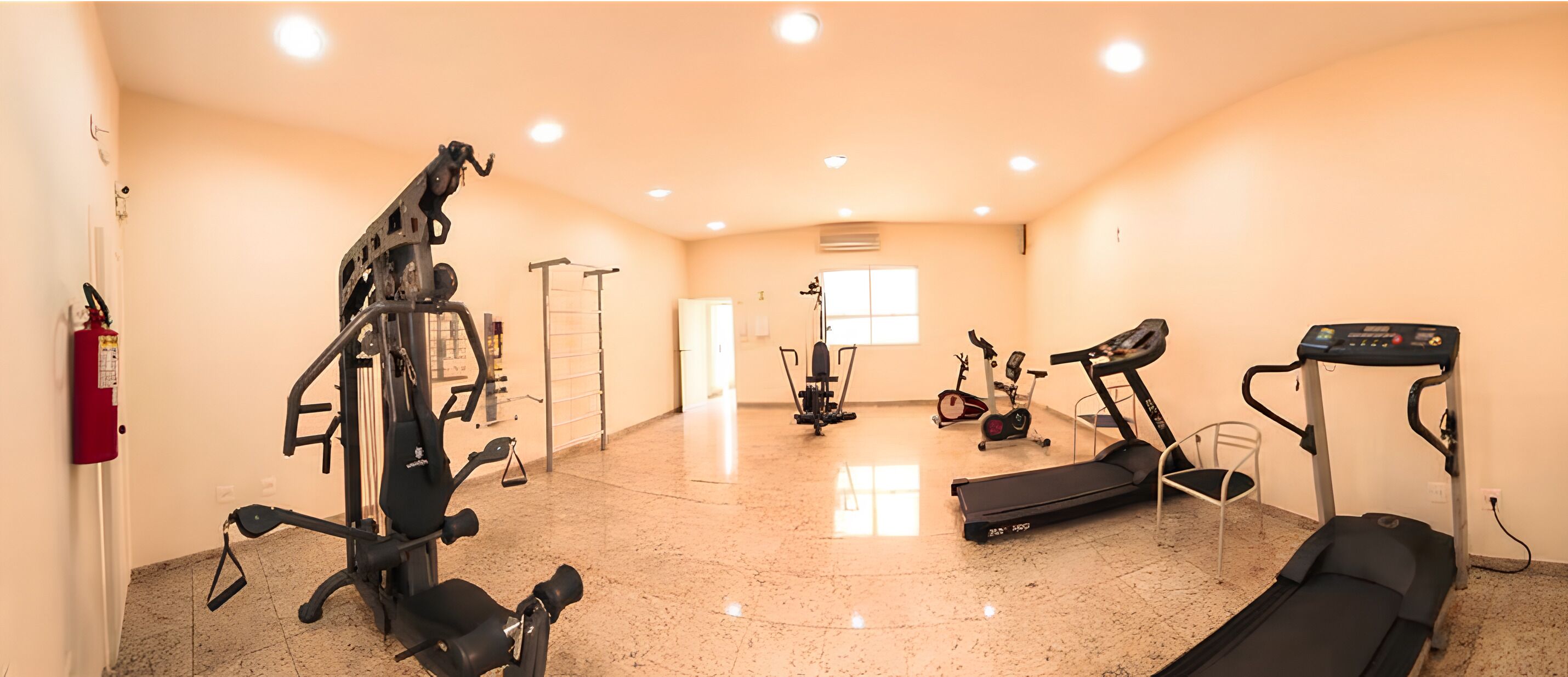 A gym with various exercise equipment including a treadmill, elliptical, and weight machines.