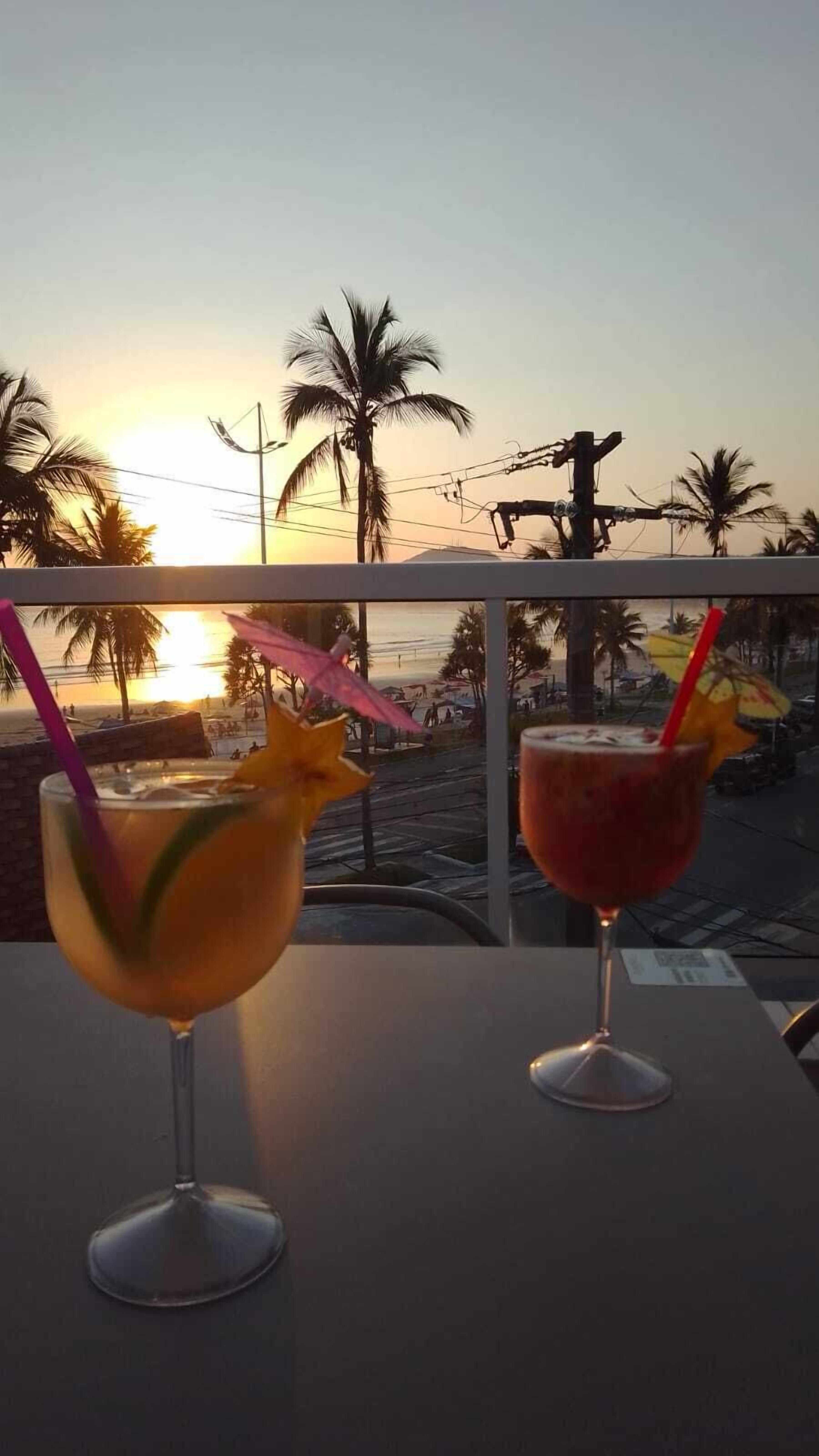 Two drinks on a table with a sunset view.