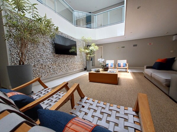 Una sala de estar moderna con una pared de piedra, un televisor de pantalla plana, dos sillones, un sofá y una mesa de centro.