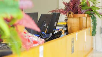A reception desk with a computer, a telephone, and a potted plant.
