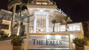 Un hotel llamado "The Falls" con una entrada destacada, amplias ventanas y un balcón con vistas a los alrededores.