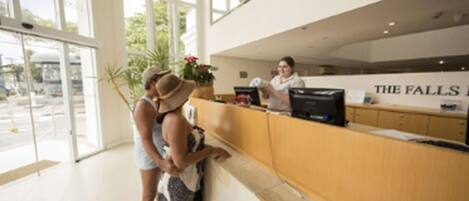 A reception area with a counter, a receptionist, and a large window with a view of the outside.