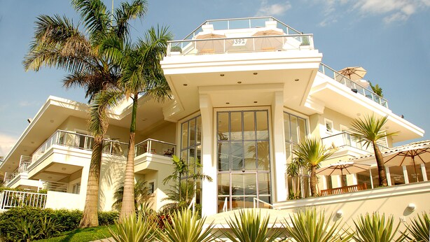 Un hotel de varios pisos con balcones, palmeras y un cielo despejado.