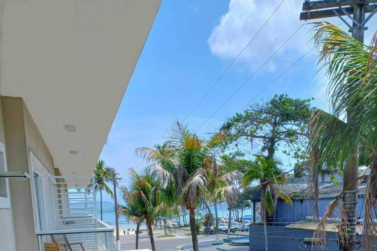 A balcony with a view of the street, palm trees, and a building in the background.
