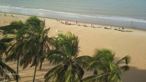 A beach with palm trees, umbrellas, and a clear view of the ocean. - Rede Andrade Solmar (João Pessoa)