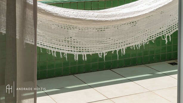A hammock on a balcony with a view of the beach and palm trees. - Rede Andrade Solmar (João Pessoa)