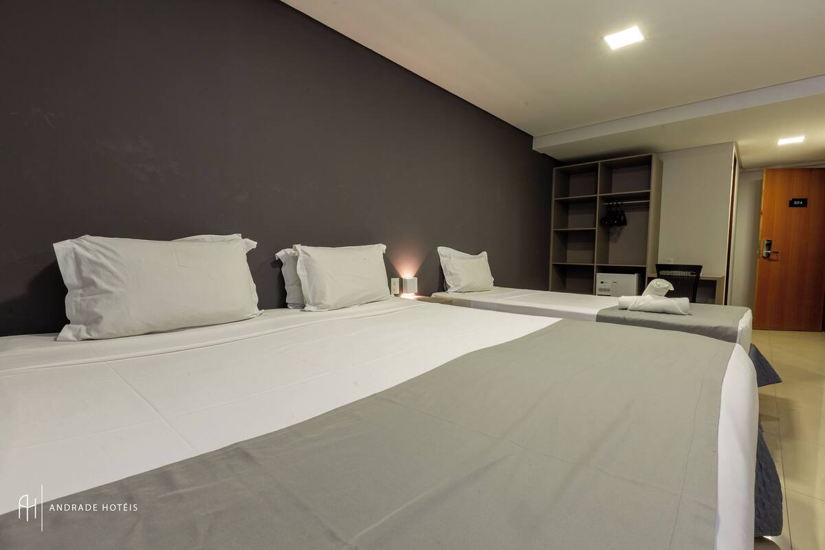 A hotel room with two beds, a wardrobe, and a desk.