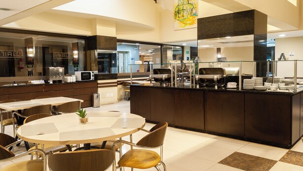 Una cocina moderna con una isla central, comedor con sillas y un espejo grande.