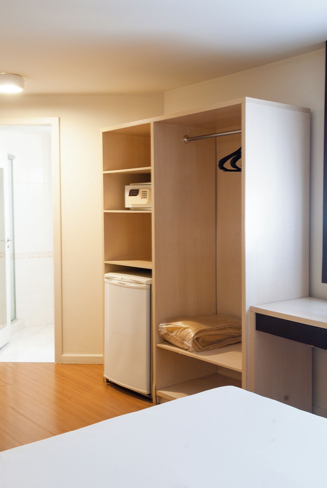 A compact, modern room with a built-in wardrobe, a small washing machine, and a neatly folded towel on the lower shelf.