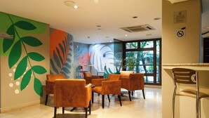 Un interior moderno con una zona de estar con sillas naranjas y una zona de bar con una silla metálica.
