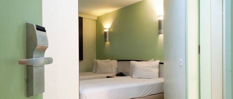 A hotel room with a bed, a wall-mounted light, and a door.