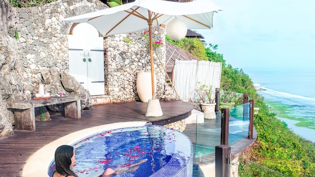 A woman relaxing in a hot tub with a view of the ocean.