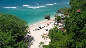 A beach with clear turquoise waters, a sandy shore, and several small huts with thatched roofs.