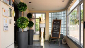 Un espace d’accueil avec un tableau noir, des plantes en pot et une fenêtre donnant sur un paysage agréable.