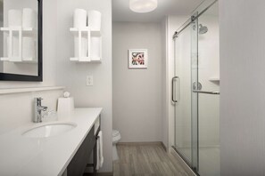 A modern bathroom with a white sink, a glass shower enclosure, and a framed picture on the wall. - Hampton Inn Duncan (Duncan)