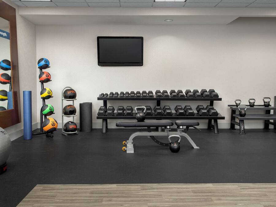 A gym with various exercise equipment, including kettlebells, dumbbells, and a stationary bike.