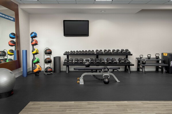 A gym with various exercise equipment, including kettlebells, dumbbells, and a stationary bike.