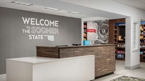 Un comptoir d’accueil avec une pancarte indiquant « Bienvenue dans l’État du Sooner », une autre pancarte indiquant « Friandises » et une troisième pancarte indiquant « Hilton ».