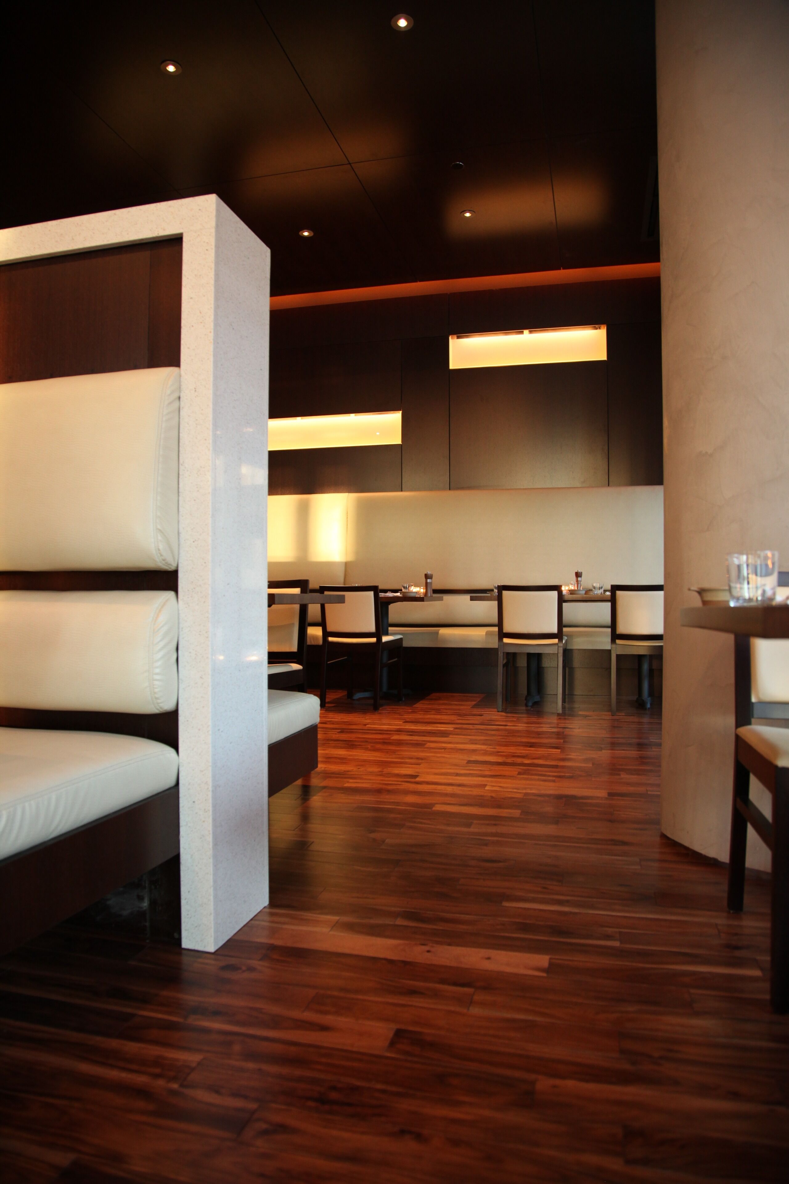 A modern restaurant with wooden flooring, cushioned seating, and a clean, minimalist design.