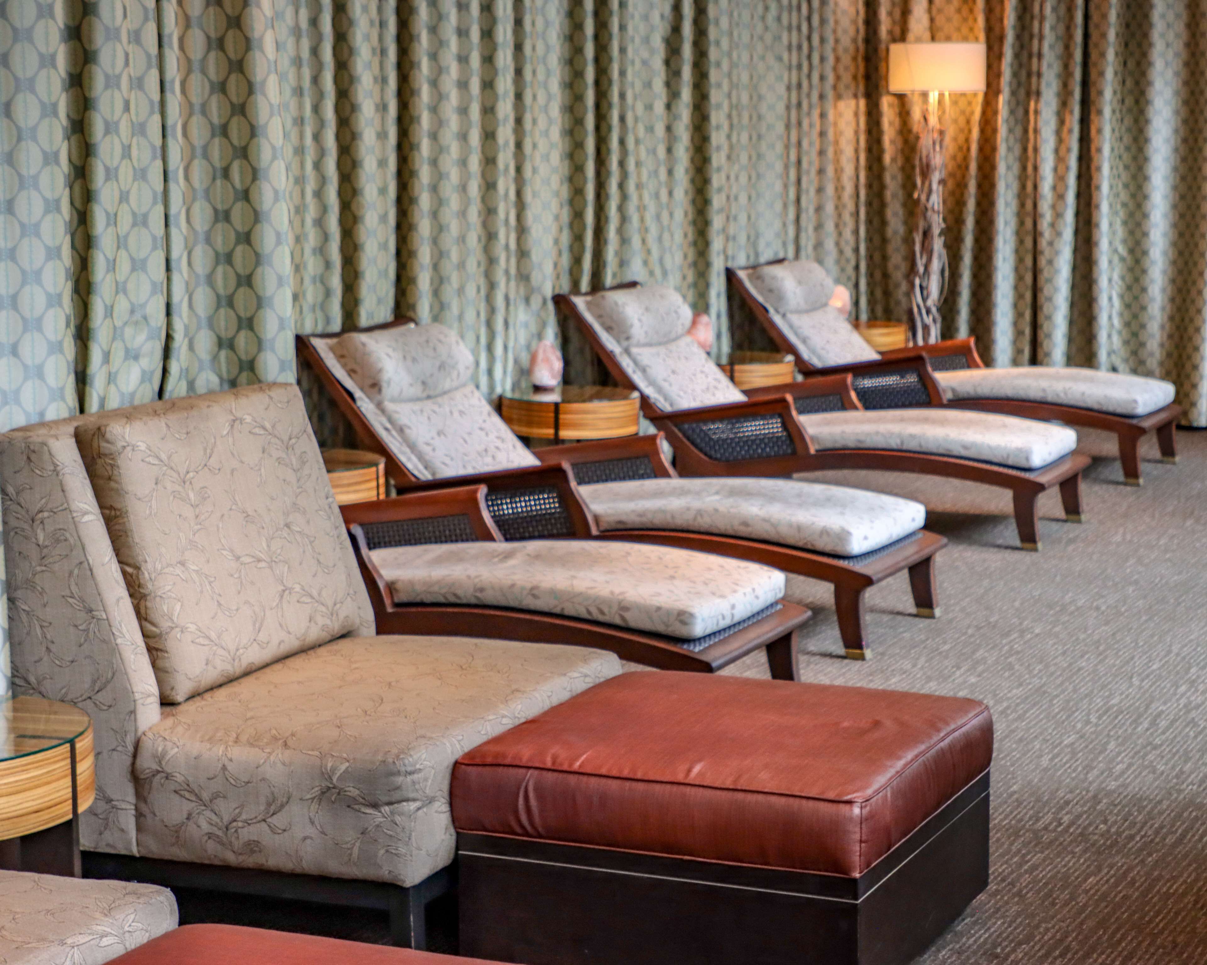 Ein Hotelzimmer mit einer Couch, zwei Sesseln und einem kleinen Hocker.