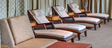 Ein Hotelzimmer mit einer Couch, zwei Sesseln und einem kleinen Hocker.