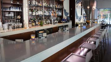 A bar area with shelves of liquor bottles, glasses, and a QR code sign.