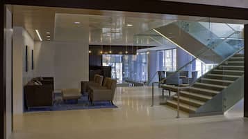 A modern lobby with a glass staircase, seating area, and a view of the interior space.
