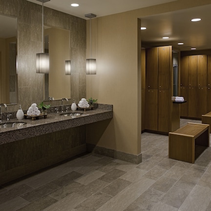 A modern bathroom with a granite countertop, two sinks, a large mirror, and wooden cabinets.