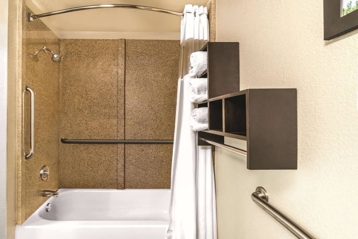 Un baño con bañera, ducha, toallero y barandilla.