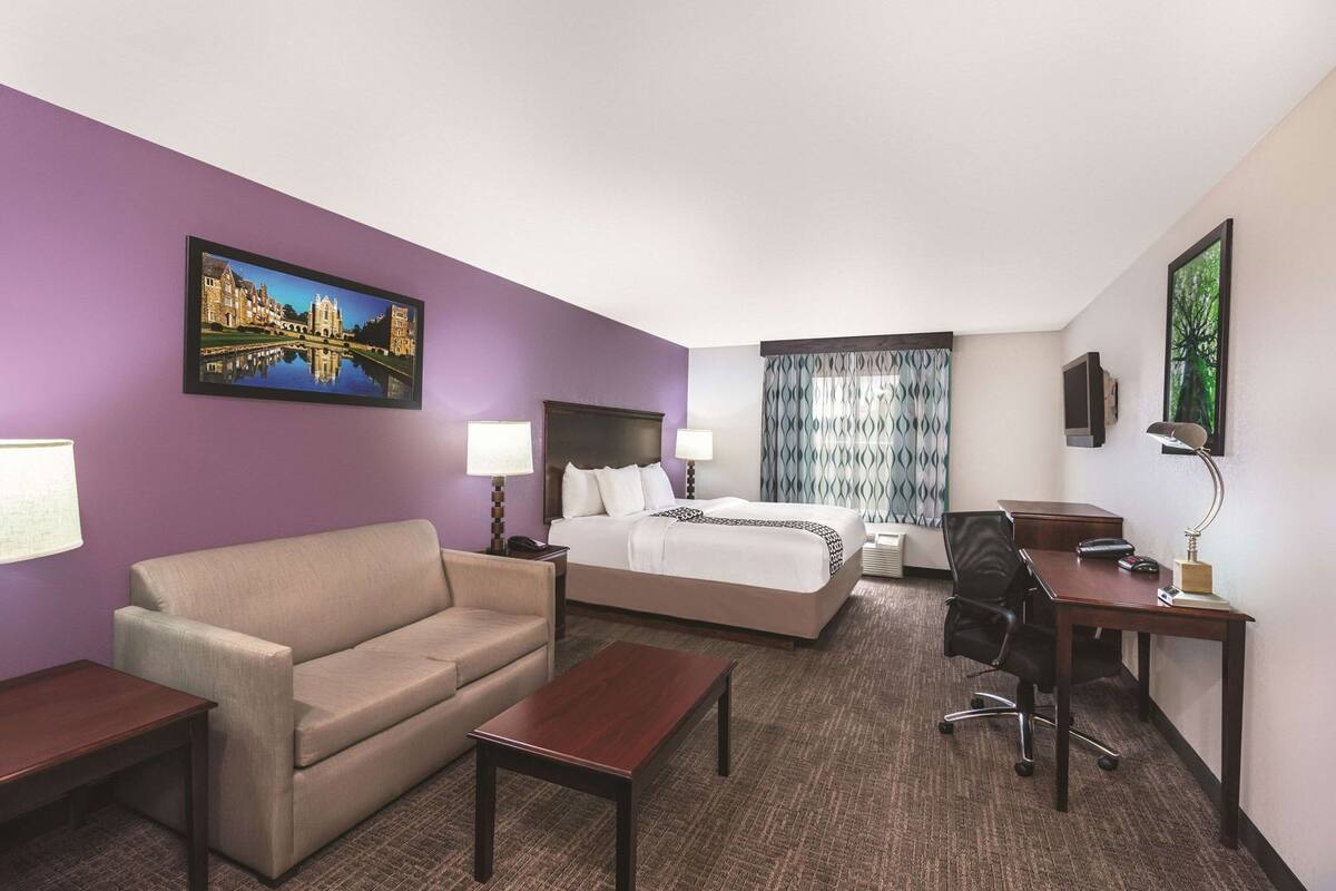 Habitación de hotel con cama, sofá, escritorio y una silla.