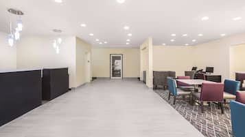Un hall d’hôtel comprenant un comptoir d’accueil, un espace salon et un tapis à motifs.