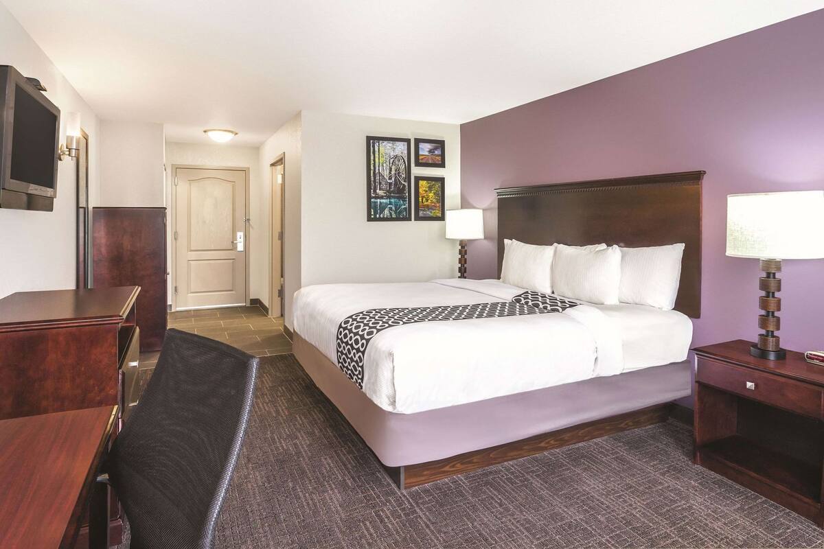 Una habitación de hotel con cama, mesitas de noche, escritorio y silla.