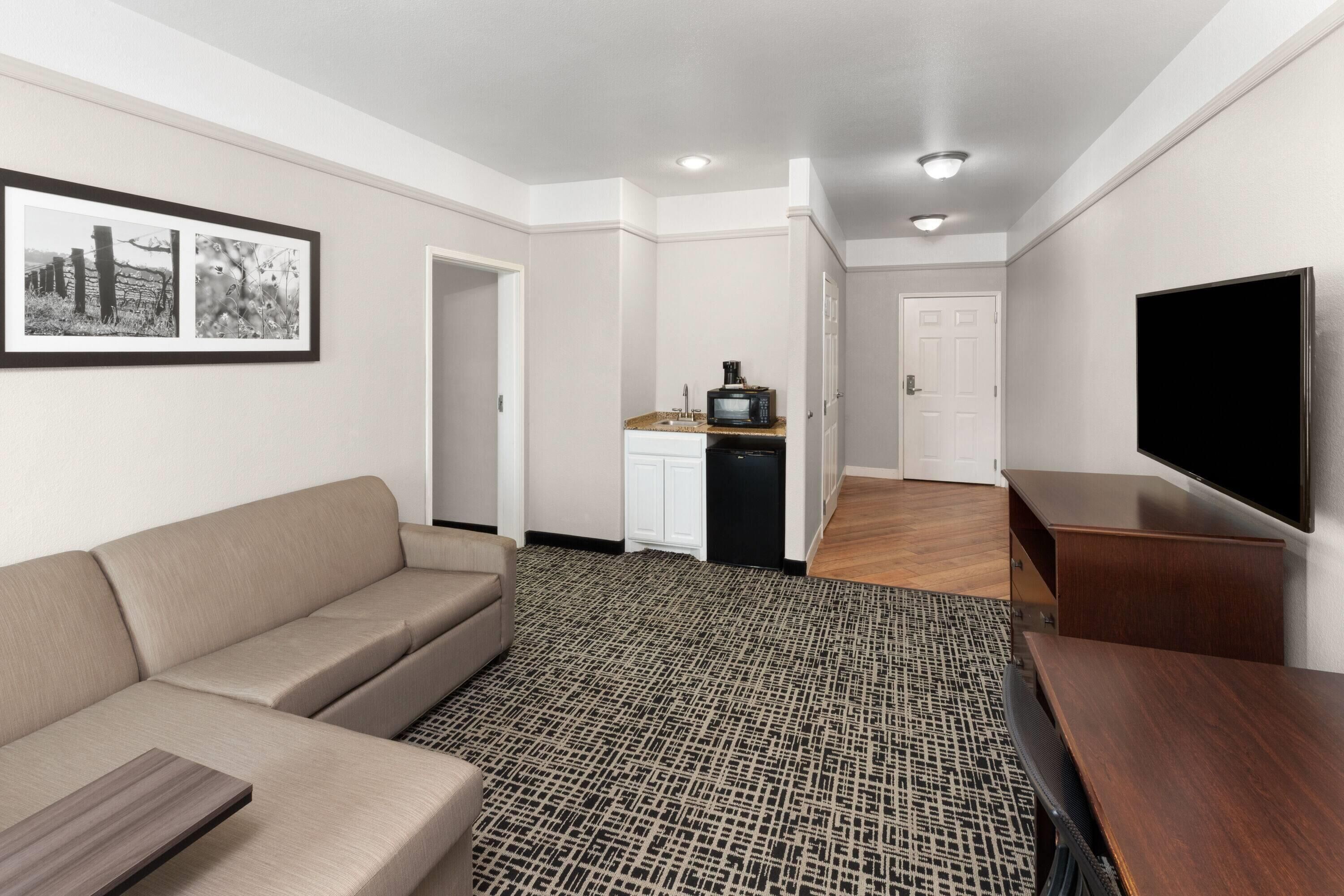 A modern living room with a sofa, a coffee machine, a TV, and a patterned rug.