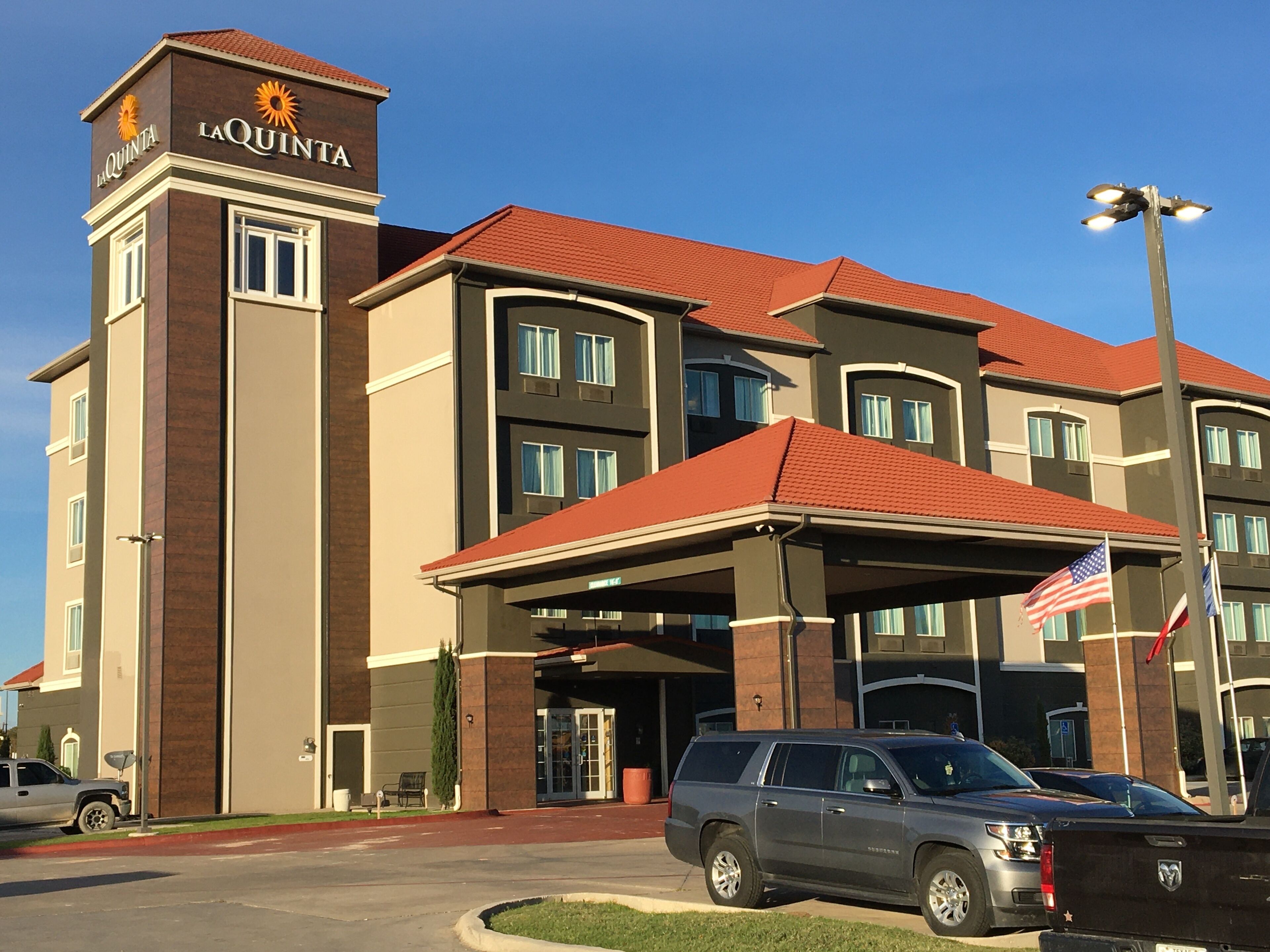 A hotel with a prominent 'La Quinta' sign, a covered entrance, and a flag.
