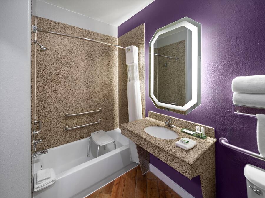 Un baño con bañera, lavamanos, espejo y ducha.