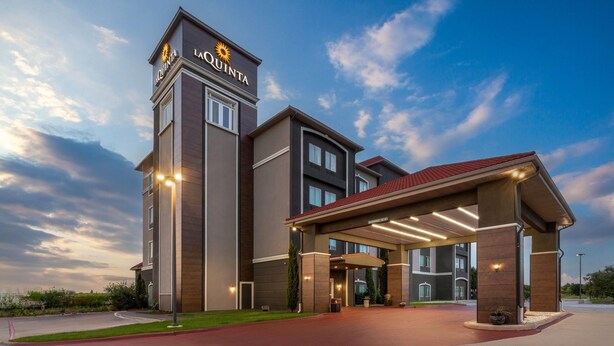 Un hotel con una torre destacada, un acceso cubierto y un césped bien cuidado.