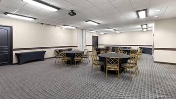 A conference room with round tables, chairs, and a carpeted floor.