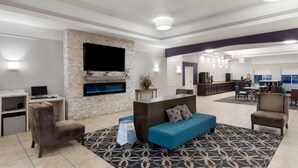 Una sala de estar moderna con una pared de acento de piedra, un televisor de pantalla plana, una chimenea, un sofá y una zona de comedor con barra.