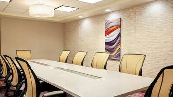 A conference room with a long table and chairs, a textured wall, and a colorful abstract painting.