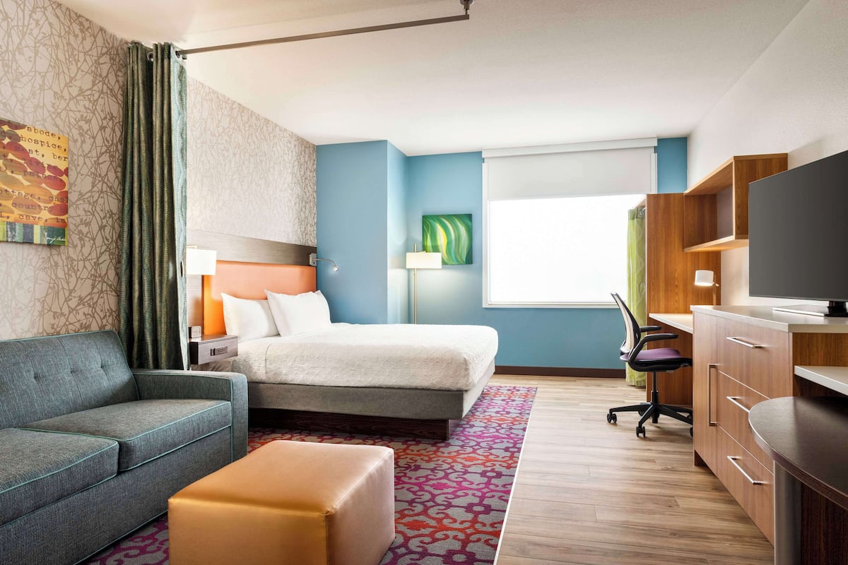 Ett hotellrum med en säng, en soffa, ett skrivbord och en tv.